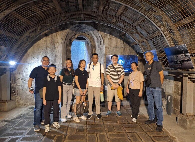 A group of people standing in a stone tunnel with a curved ceiling. 2
