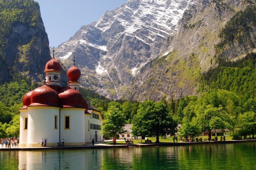 A church with red domes, a lake, and a mountainous backdrop. 2