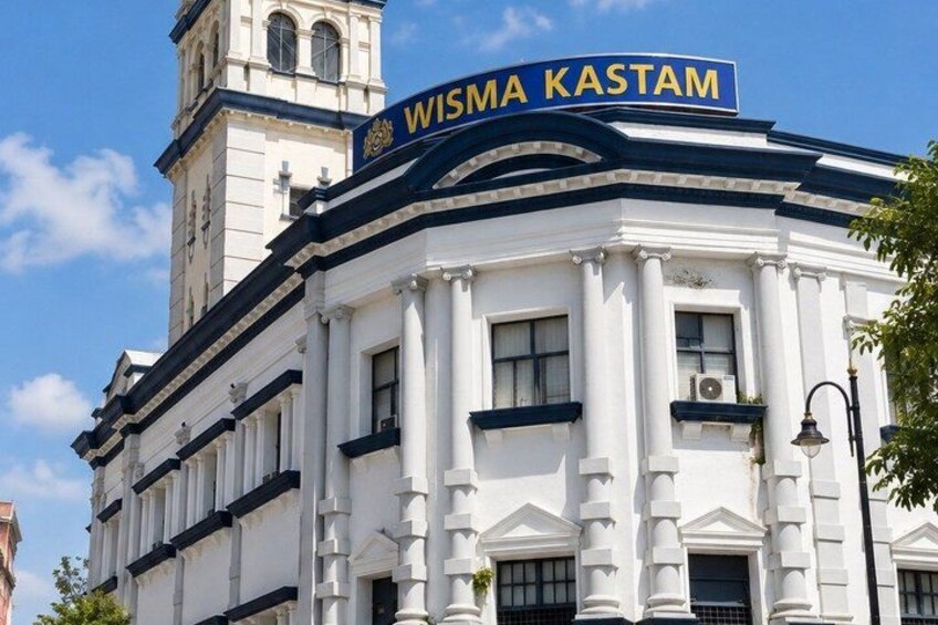 A white building with a blue sign that reads 'WISMA KASTAM'. 2