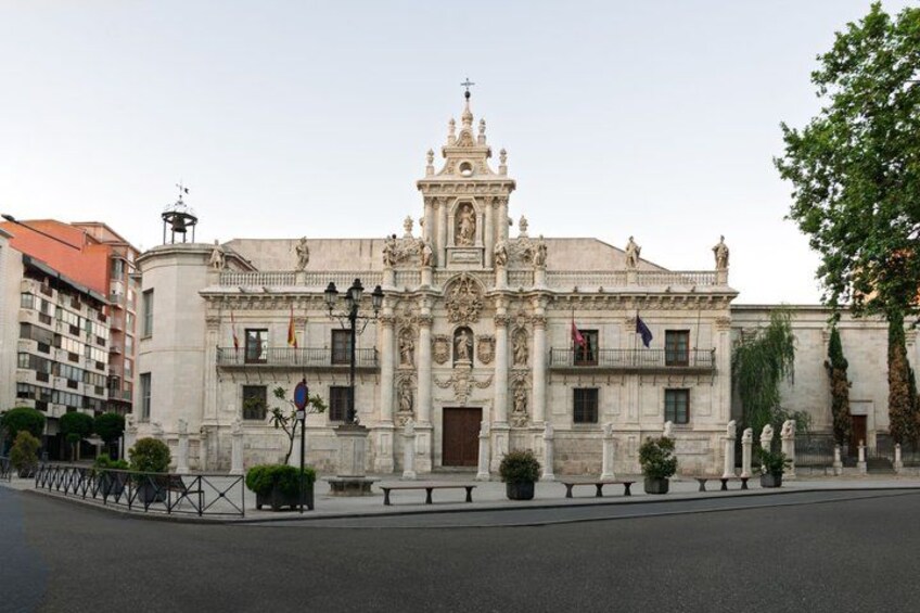 A historic building with ornate architecture, a prominent bell tower, and a statue in front. 2