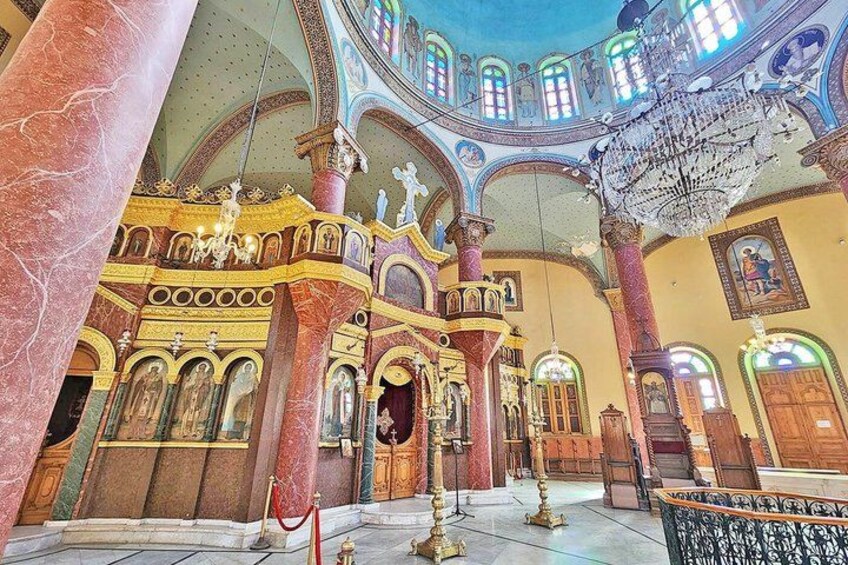 An ornate church interior with marble columns, stained glass windows, and a chandelier. 1