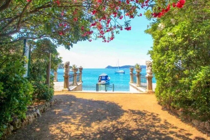 A coastal pathway leading to a beach with boats in the water and a clear sky. 5