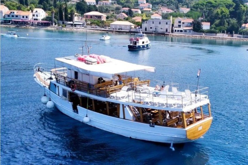 A white boat with a yellow front, docked in a harbor with other boats and buildings in the background. 1