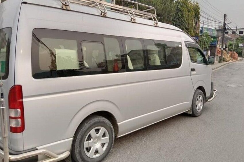 A silver van parked on a street with a ladder on the roof. 3