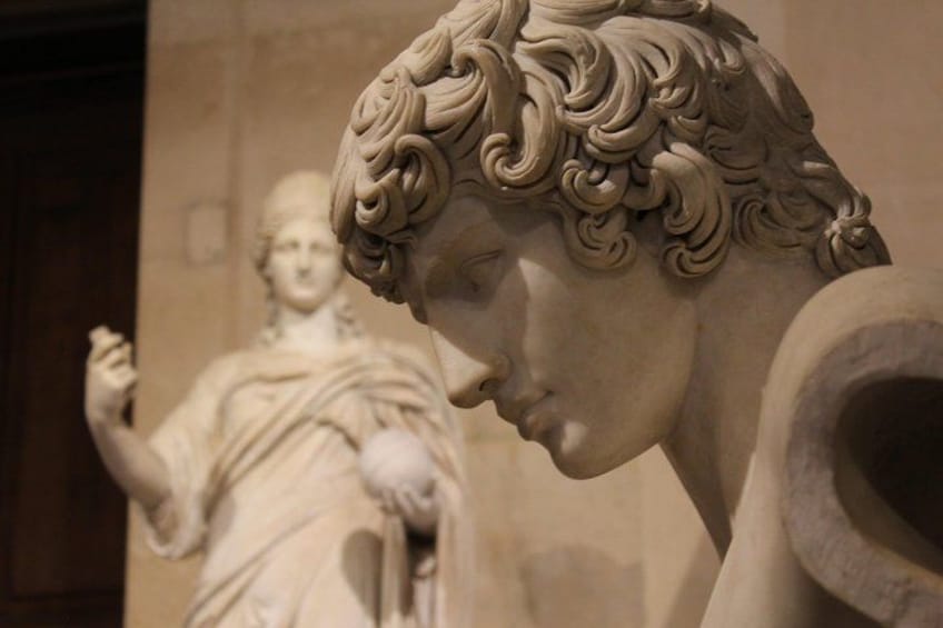 A marble sculpture of a woman with intricate curls, set against a plain wall. 3