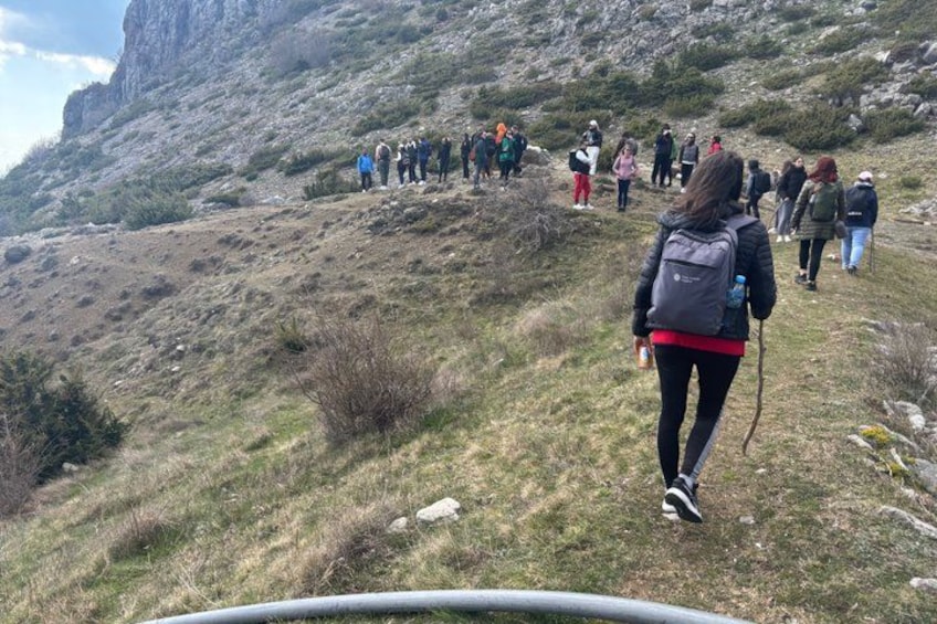 A group of hikers ascending a grassy hillside with rocky terrain. 5