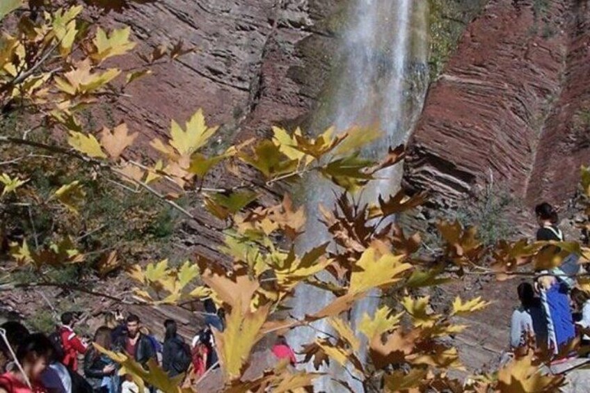 A waterfall, rocky cliffs, and people observing the scenery. 2