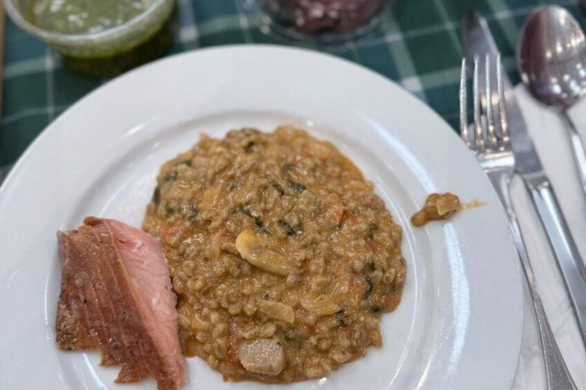 A plate of lentil soup with a piece of meat on the side, served on a white plate. 5