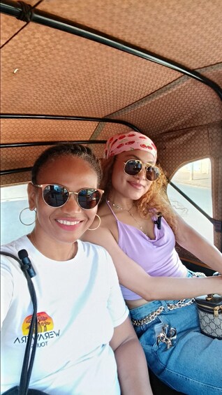 Two people seated in a vehicle with a patterned fabric interior. 5
