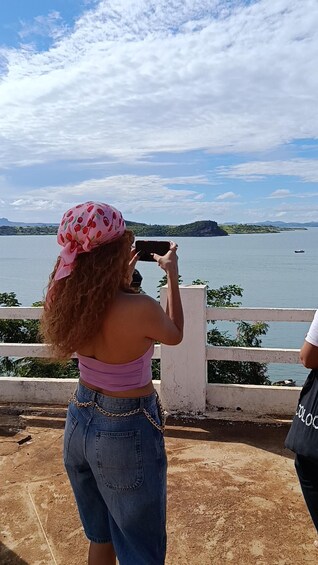 A person taking a photo of a body of water with a distant island. 1