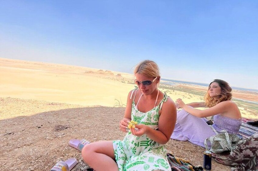 Two people sitting on a blanket in a desert landscape. 2