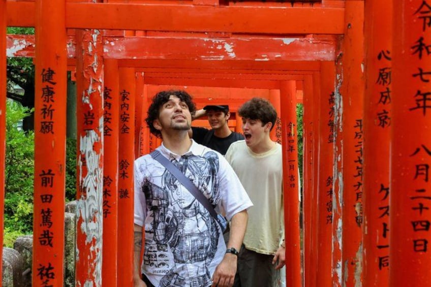 A person standing in front of a red torii gate with Japanese characters. 1
