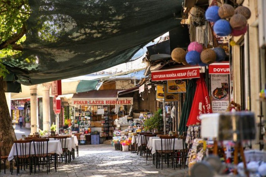 A street market with tables and chairs, shops, and signs. 2