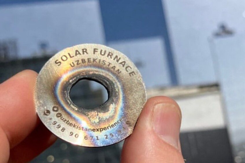 A metallic object with text 'SOLAR FURNACE UZBEKISTAN' and a contact number. 2