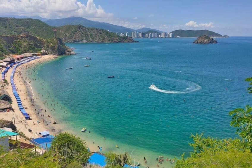A coastal beach with clear turquoise waters, a sandy shore, and a few boats. 1