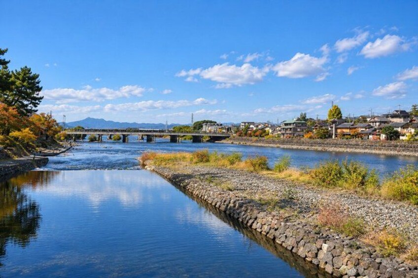A river with a stone embankment, a bridge, and buildings in the background. 2