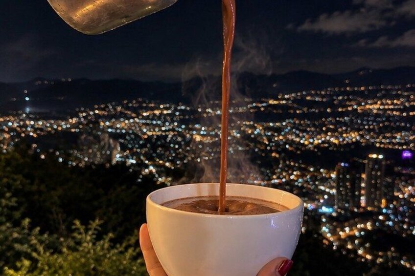 A cup of coffee being poured with a cityscape in the background. 4