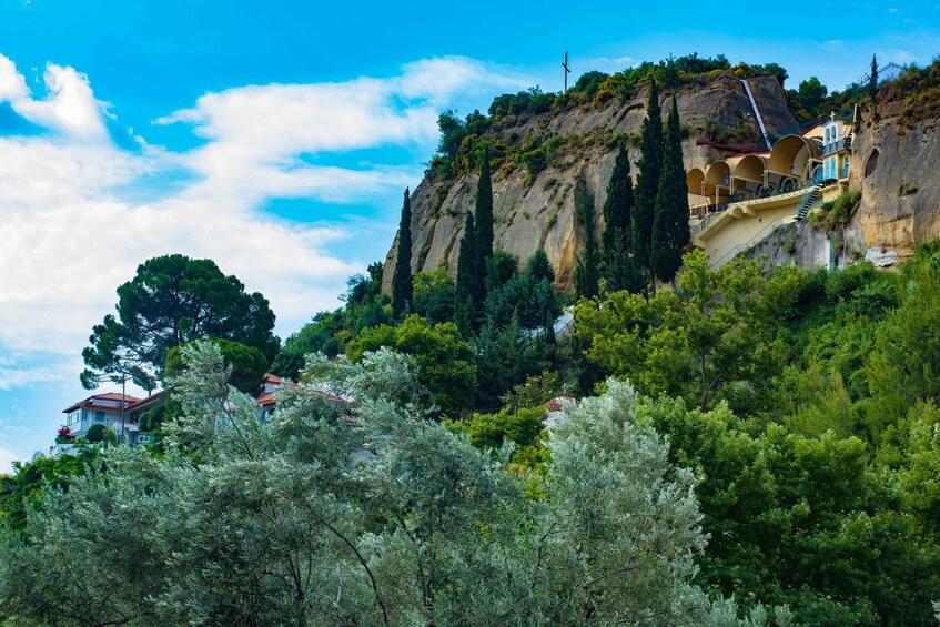 Eine Berglandschaft mit einer Kirche auf einem Felsen, üppigem Grün und blauem Himmel. 5