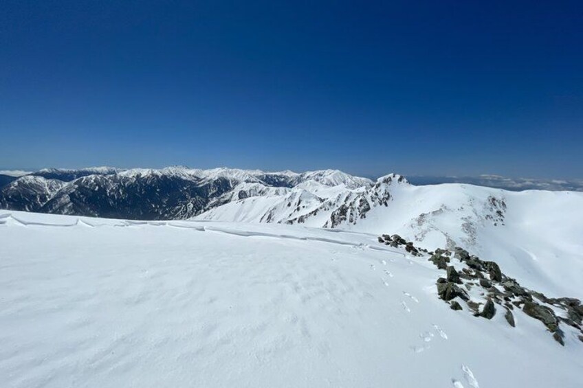 A snow-covered mountain range under a clear blue sky. 4