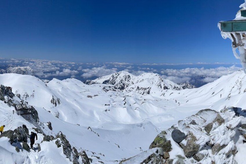 A snow-covered mountain landscape with rocky outcrops and a clear blue sky. 2