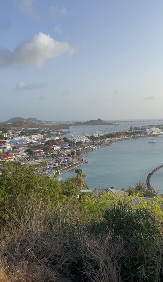 A coastal town with buildings along the waterfront, a clear sky, and a distant mountain range. 5