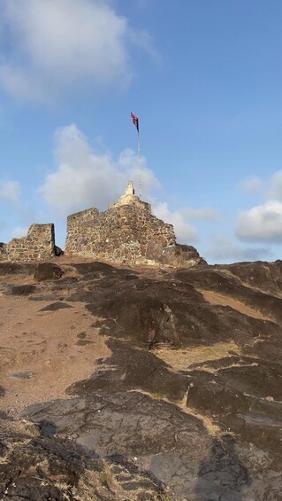 A stone fortress with a flag on top, surrounded by rocky terrain. 2