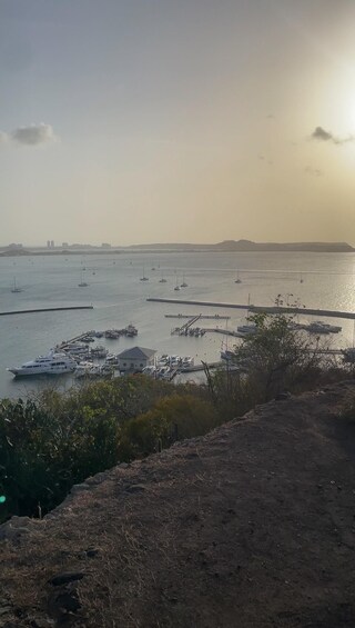 A coastal landscape with a marina, boats, and a distant city skyline. 4