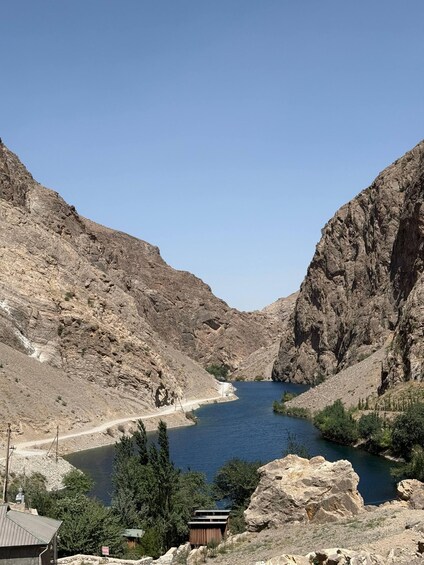 A rocky canyon with a river, a road, and a small building. 3