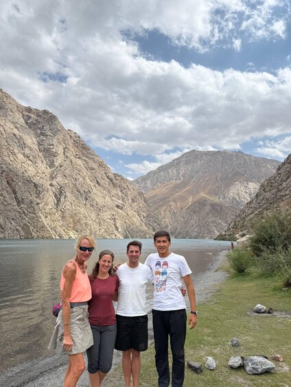 A group of people standing by a lake with mountains in the background. 5