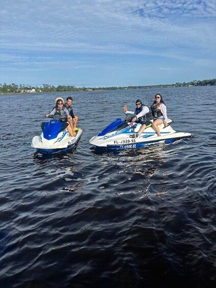 Two people on jet skis on a calm lake with a clear sky. 1