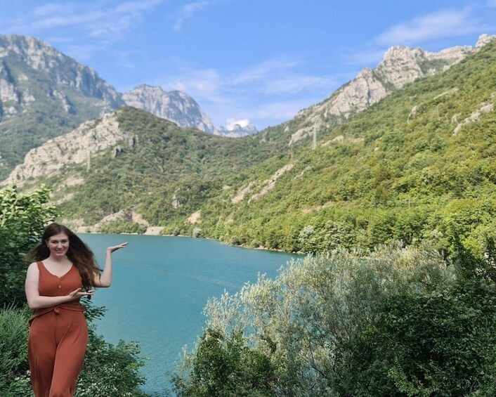 A woman walking by a lake with mountains in the background. 5