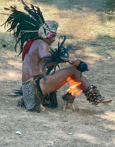 A person in traditional attire with a fire burning on the ground. 5