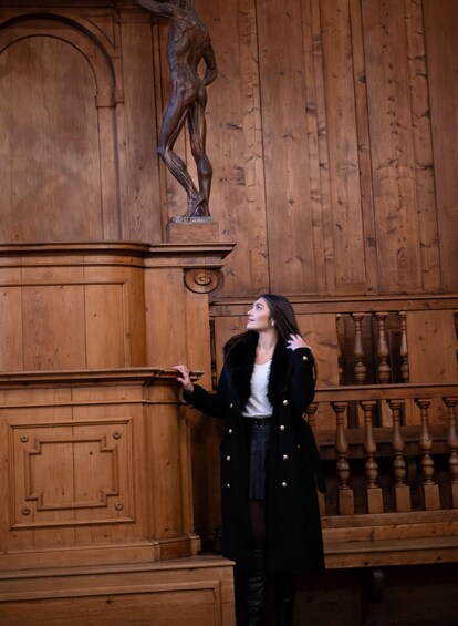 A person standing in front of a wooden panel with a statue of a figure. 4