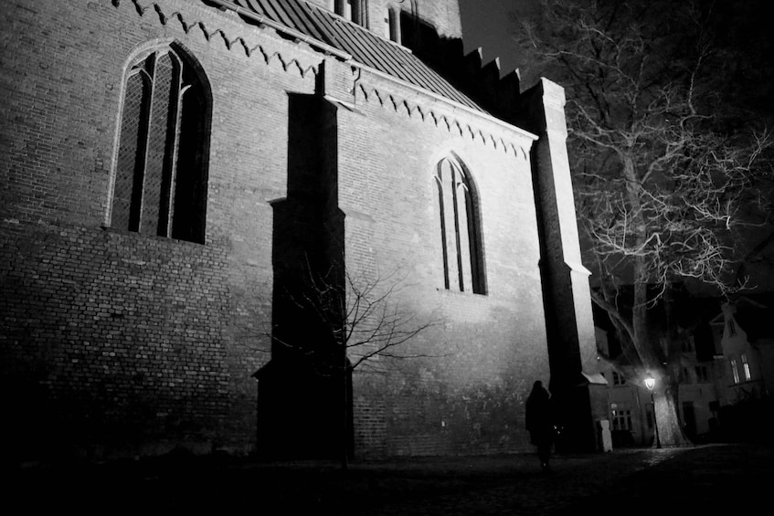 A brick building with arched windows and a tall tower at night. 1