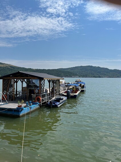 A dock with boats, a wooden structure, and a lake with hills in the background. 2