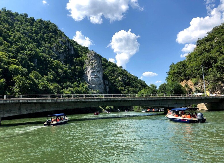 A river with boats, a bridge, and a large rock formation. 1