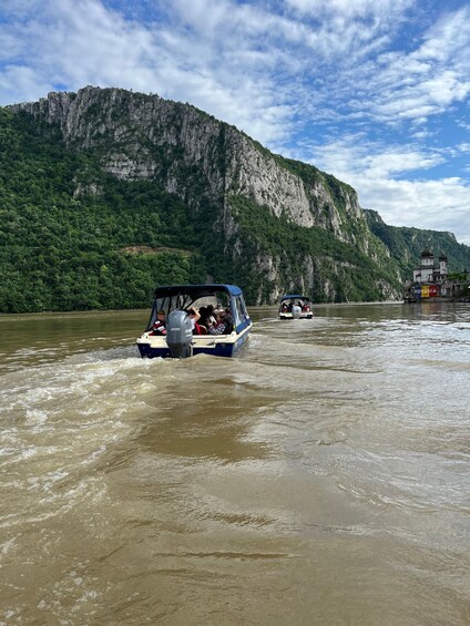 A boat moving through a river with a mountainous landscape in the background. 5