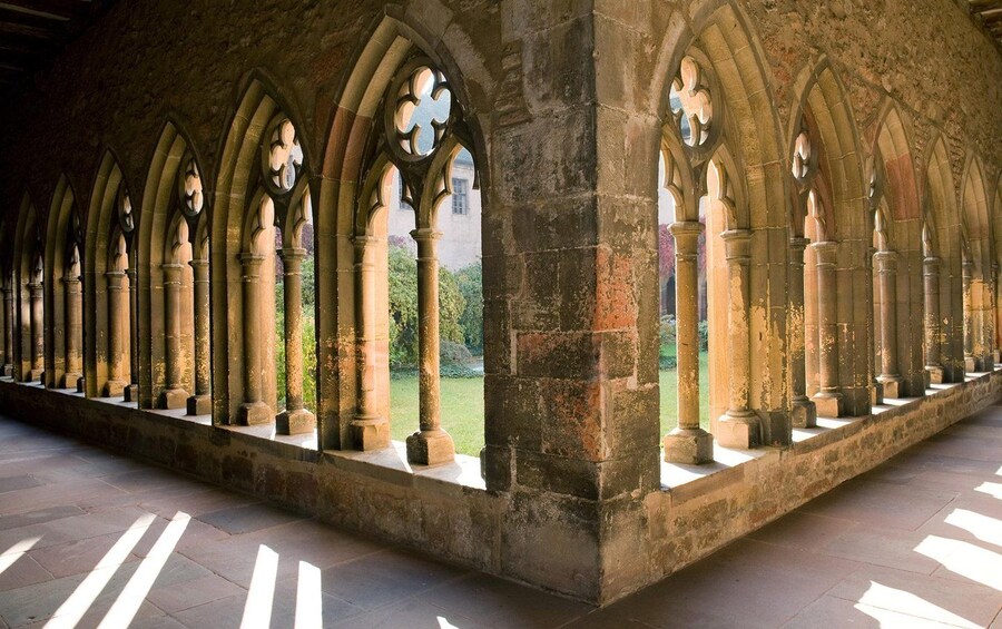A series of arched windows with stone columns, a stone floor, and a view of greenery outside. 5