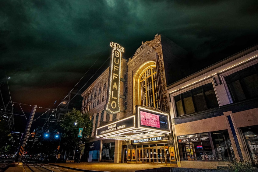 A theater with illuminated marquee and ticket office. 1