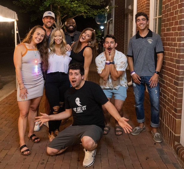 A group of people posing for a photo on a brick pavement at night. 5