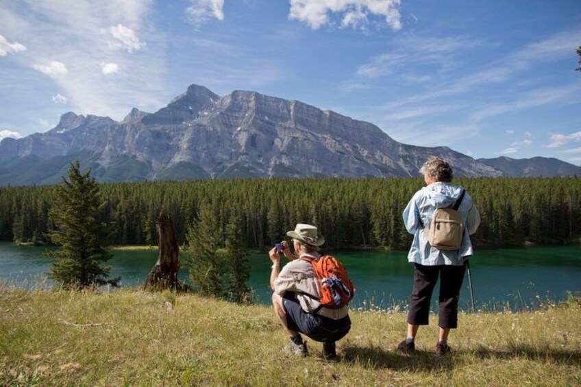 Two people hiking near a lake with mountains in the background. 2