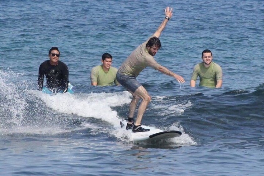 A person surfing on a wave with others in the water. 3