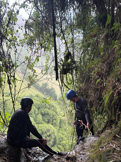 Zwei Personen seilen sich an einem felsigen Hang ab, umgeben von dichtem Wald und mit freiem Blick auf das Tal. 2