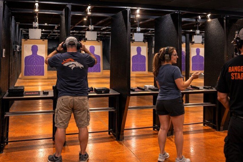 A shooting range with targets and individuals aiming at them. 5