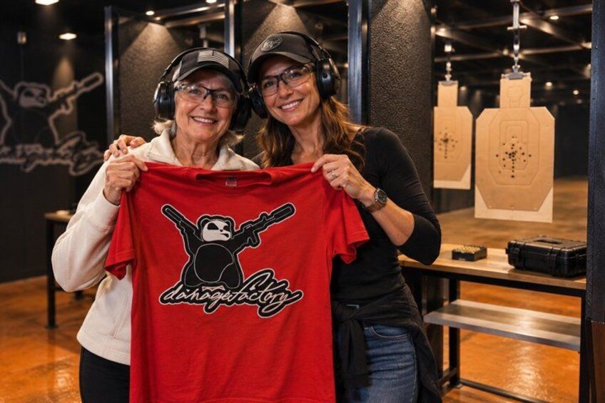 Two people holding a red t-shirt with a graphic and text. 2