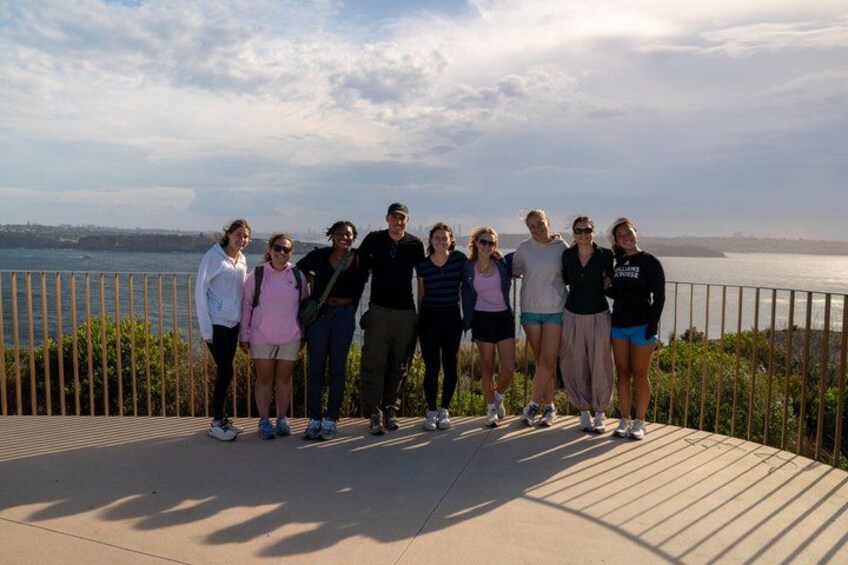 A group of people standing on a wooden deck overlooking a body of water. 4