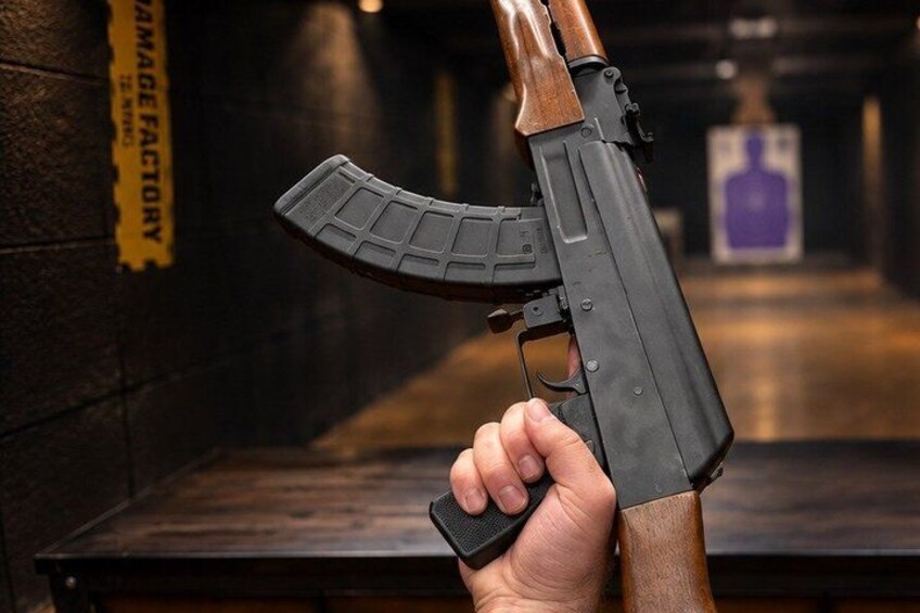 A person holding a rifle with a magazine and a wooden stock. 5