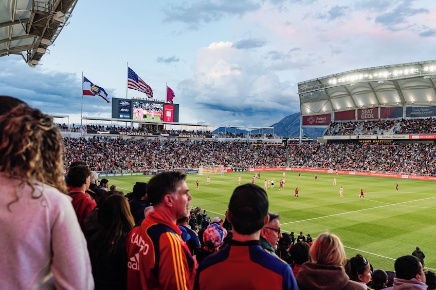 Un estadio lleno de espectadores, un campo de fútbol y un marcador. 1