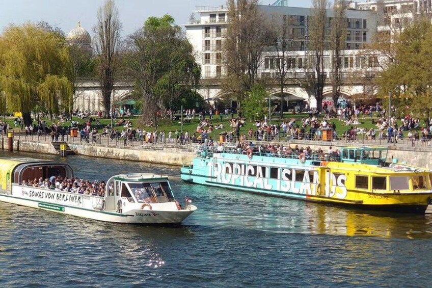 A river with boats, a park with people, and buildings in the background. 5