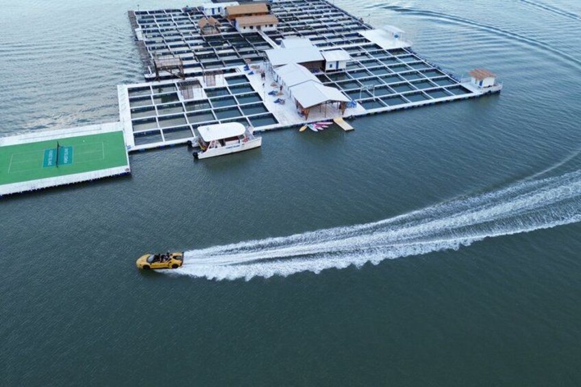 A floating structure with a dock, a small boat, and a yellow speedboat creating a wake. 1